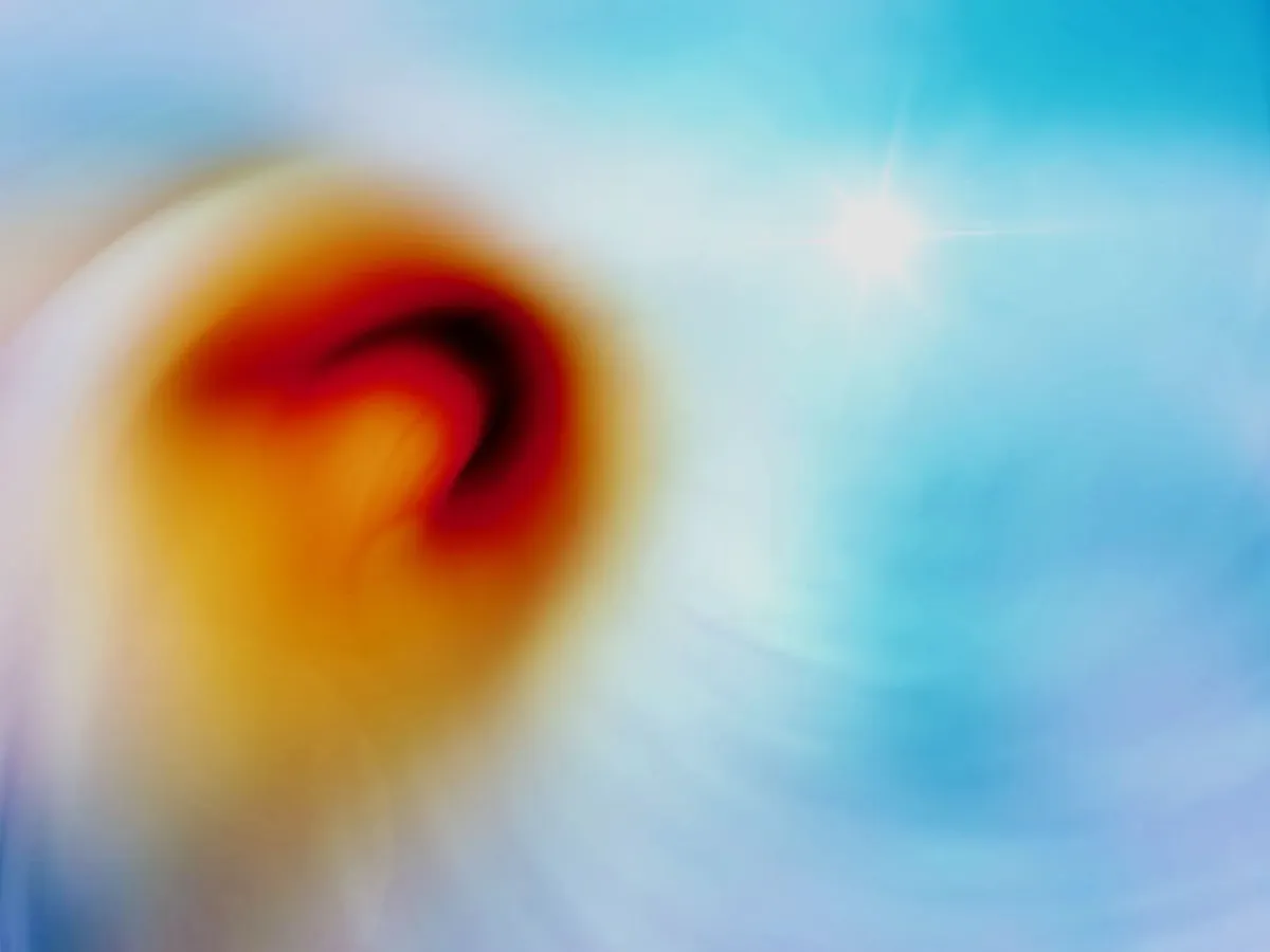 Abstract image of what might be an orange and yellow flower against a blue sky. The mood is ethereal.