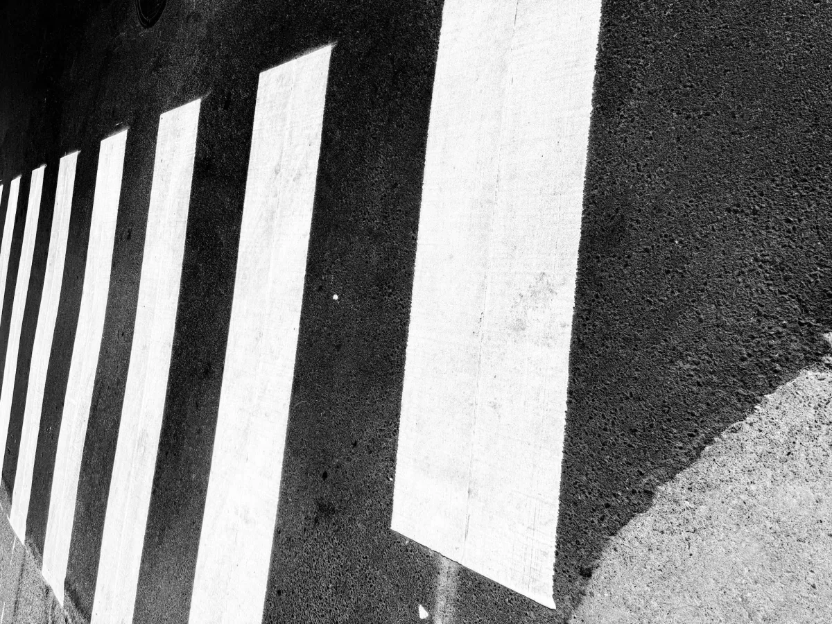 Abstract black and white photo of vertical white stripes against a dark concrete wall.