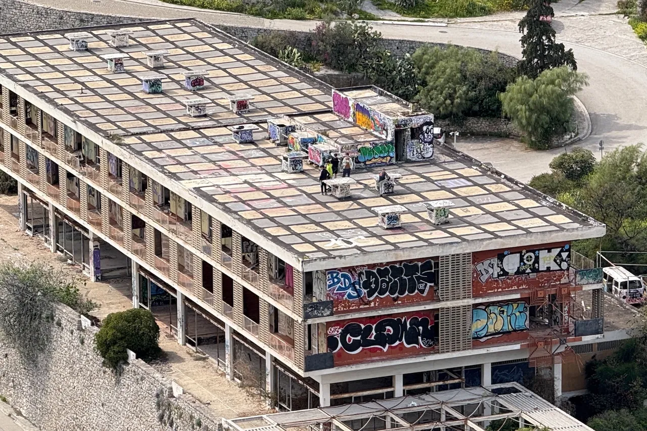Photograph taken from a distance of some people on a graffiti covered abandoned hotel. Can't tell what's going on.