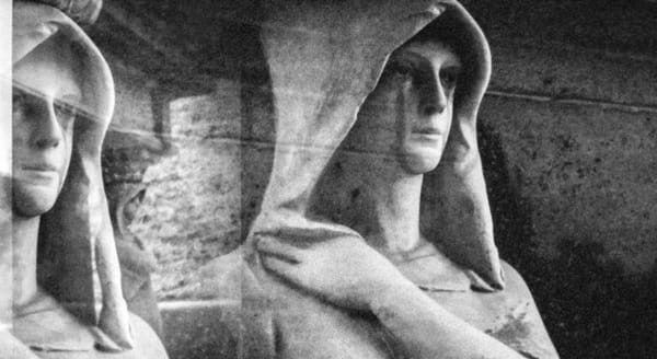 Black and white photo of a cemetery statue of a cloaked figure looking wistful. Water stains drip from its eyes like tears.